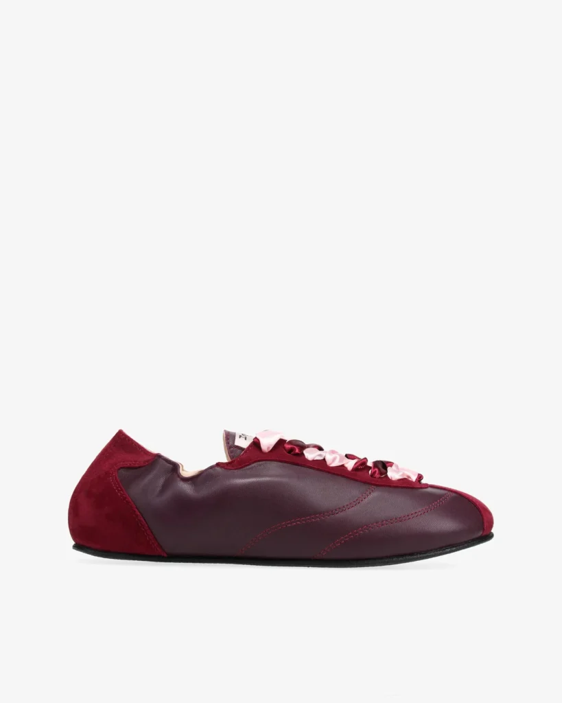 Burgundy low-profile sneaker with suede heel, leather panels, black sole, and pink-and-burgundy laces on a white background