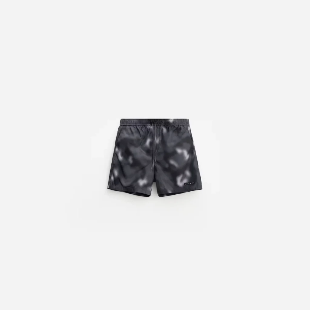 Black camouflage swim shorts with elastic drawstring waist and small rectangular logo patch, displayed on white background