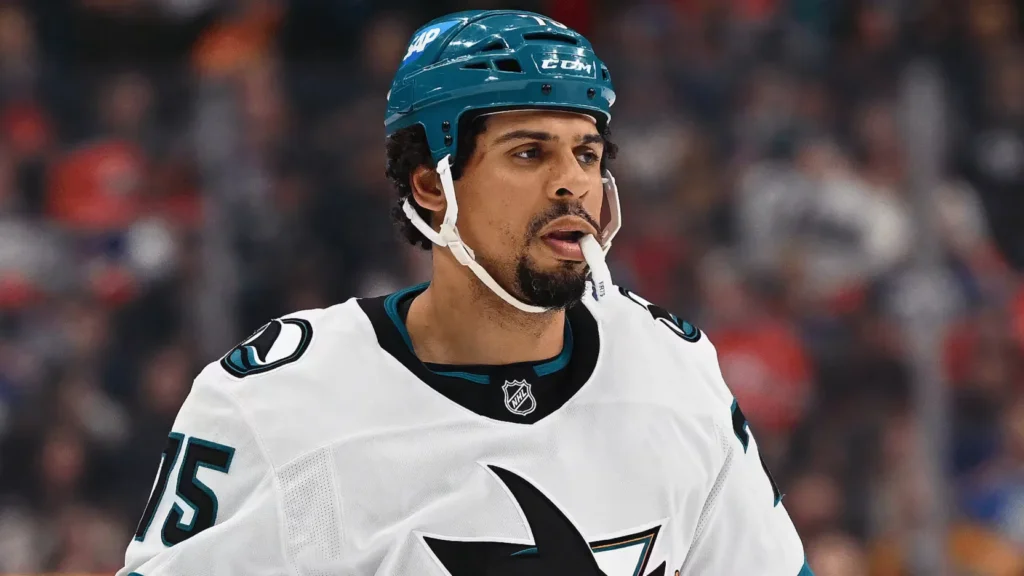 Hockey player Reaves in a teal helmet and white jersey with number 75, shown against a blurred arena crowd