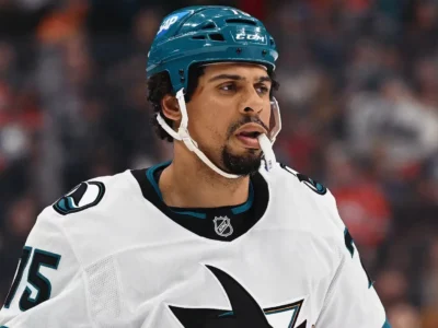 Hockey player Reaves in a teal helmet and white jersey with number 75, shown against a blurred arena crowd