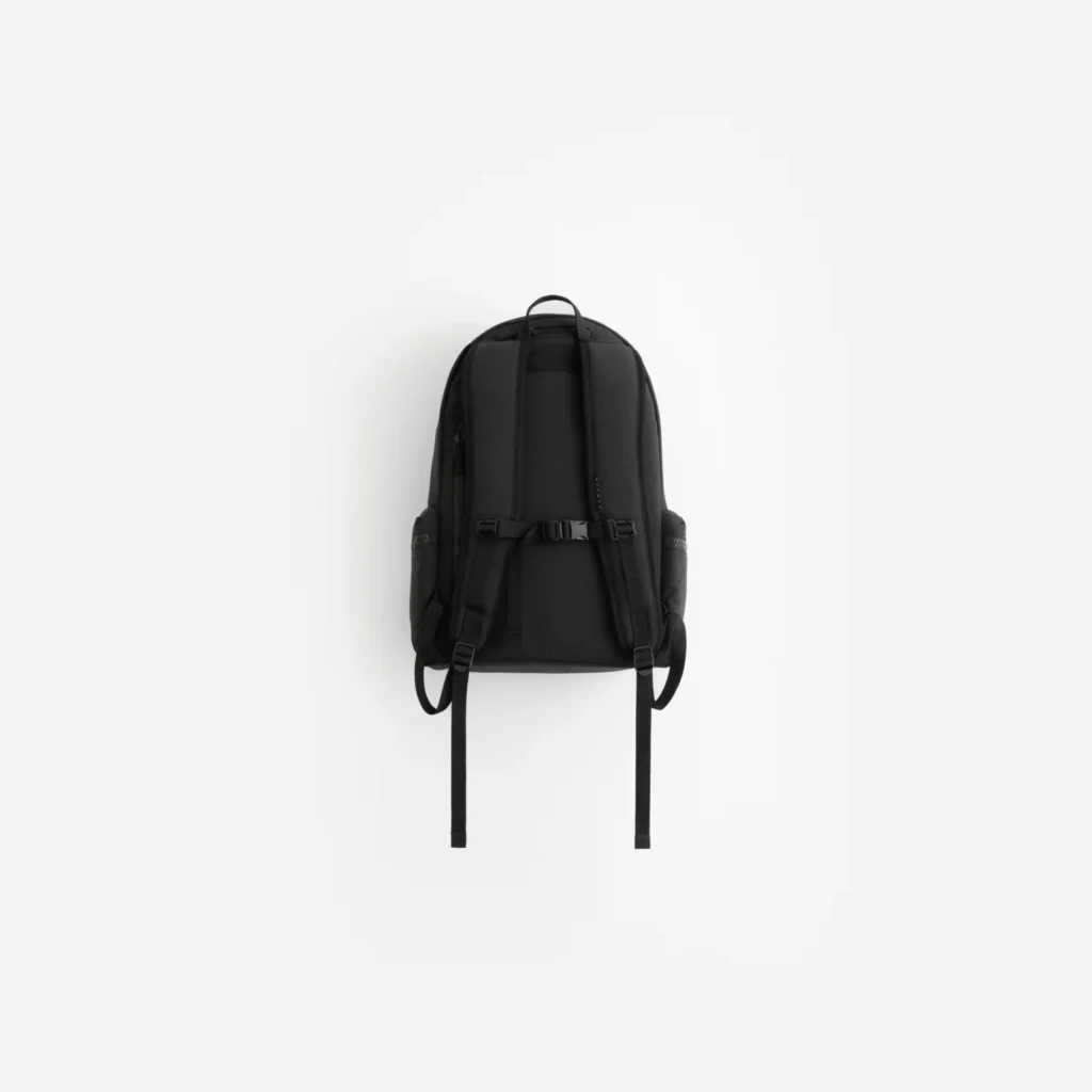 Black backpack with padded shoulder straps, waist strap, side pockets, and top handle on a white background
