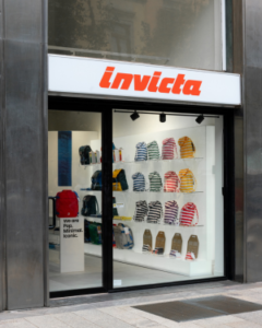 Invicta storefront with red logo, glass display windows showing colorful striped socks and accessories