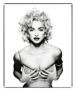 Black-and-white portrait of a woman with curly hair in a jeweled off-shoulder dress, hands across her chest, framed in white