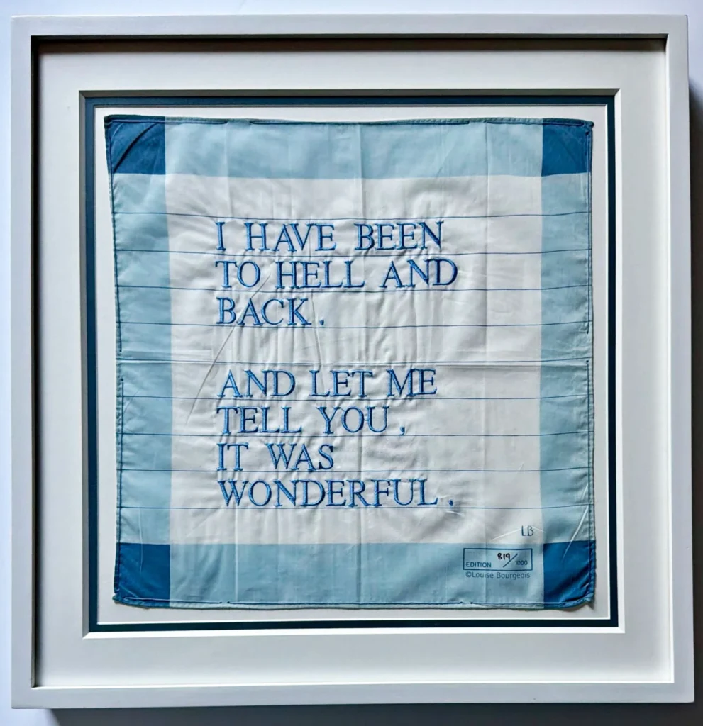 Framed blue-and-white textile artwork with embroidered text, “I HAVE BEEN TO HELL AND BACK. AND LET ME TELL YOU, IT WAS