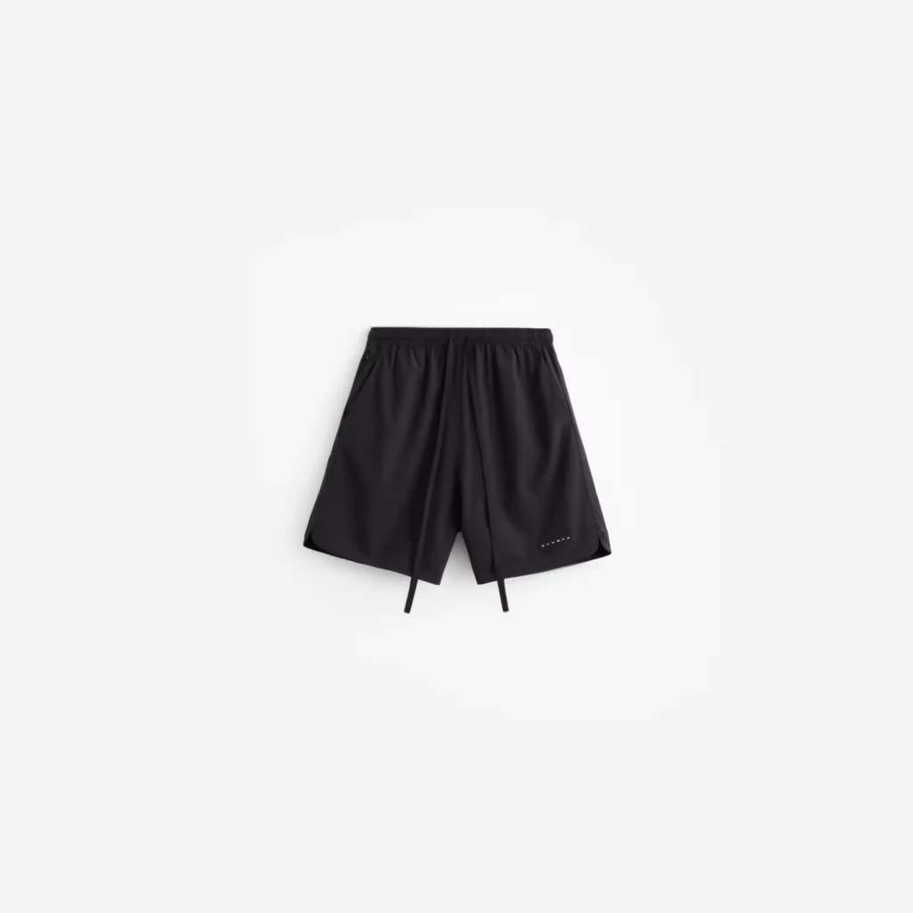 Black nylon shorts with an elastic waistband, long drawstrings, and small reflective accents on a white background