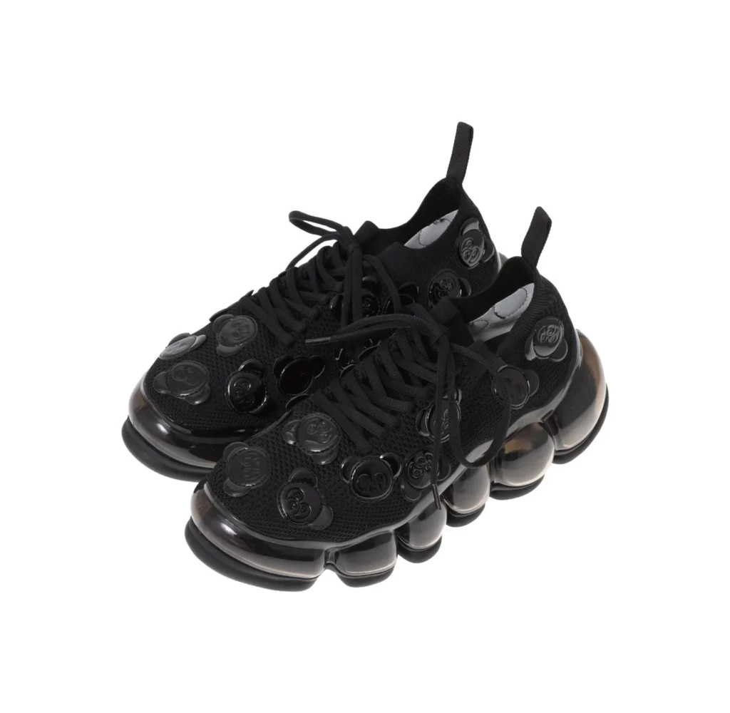 Pair of black lace-up sneakers with circular embossed details and segmented translucent bubble soles on a white background