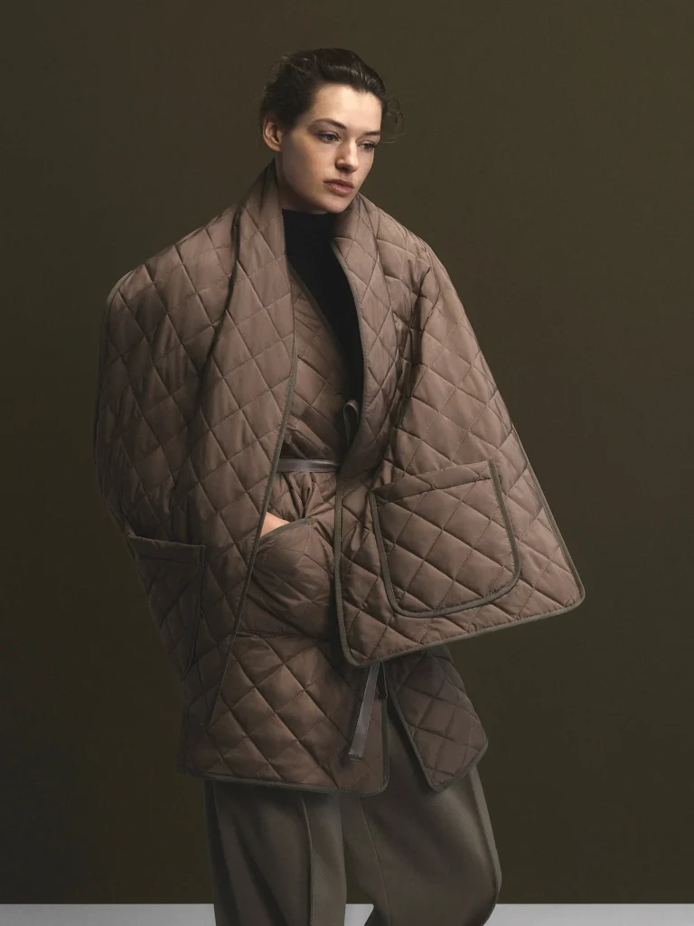 Model poses in a brown diamond-quilt wrap jacket with oversized pockets over a black top and wide-leg trousers