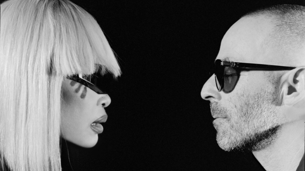 Black-and-white close-up of Erykah Badu and The Alchemist facing each other in profile, both wear dark sunglasses against
