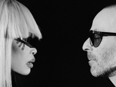 Black-and-white close-up of Erykah Badu and The Alchemist facing each other in profile, both wear dark sunglasses against