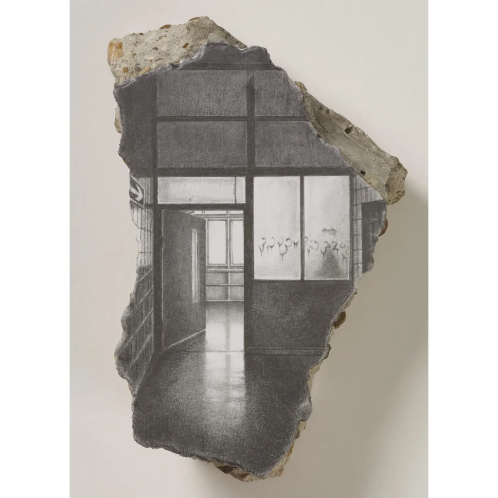 Jagged concrete fragment featuring a black-and-white drawing of a modern building entrance with windows and graffiti