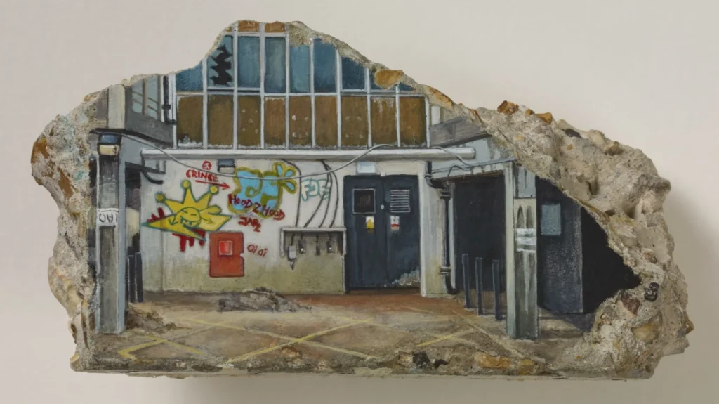 Sculptural model of a graffiti-covered building entrance embedded in an irregular chunk of concrete and rubble