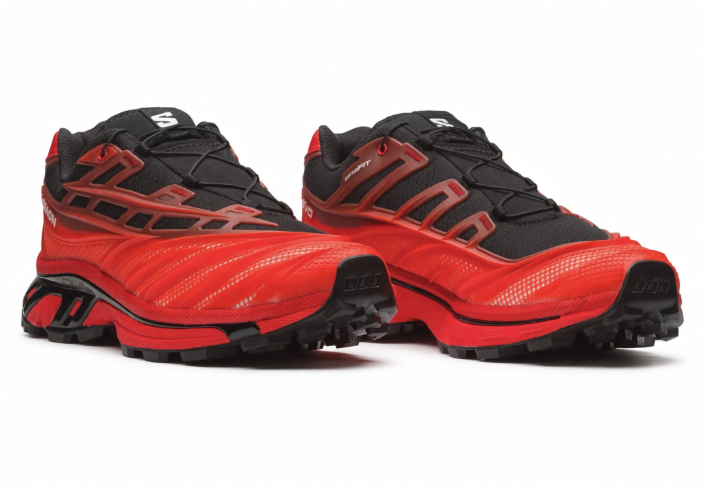 Pair of red and black Salomon trail shoes with rugged black lugs and angular red overlays on a white background