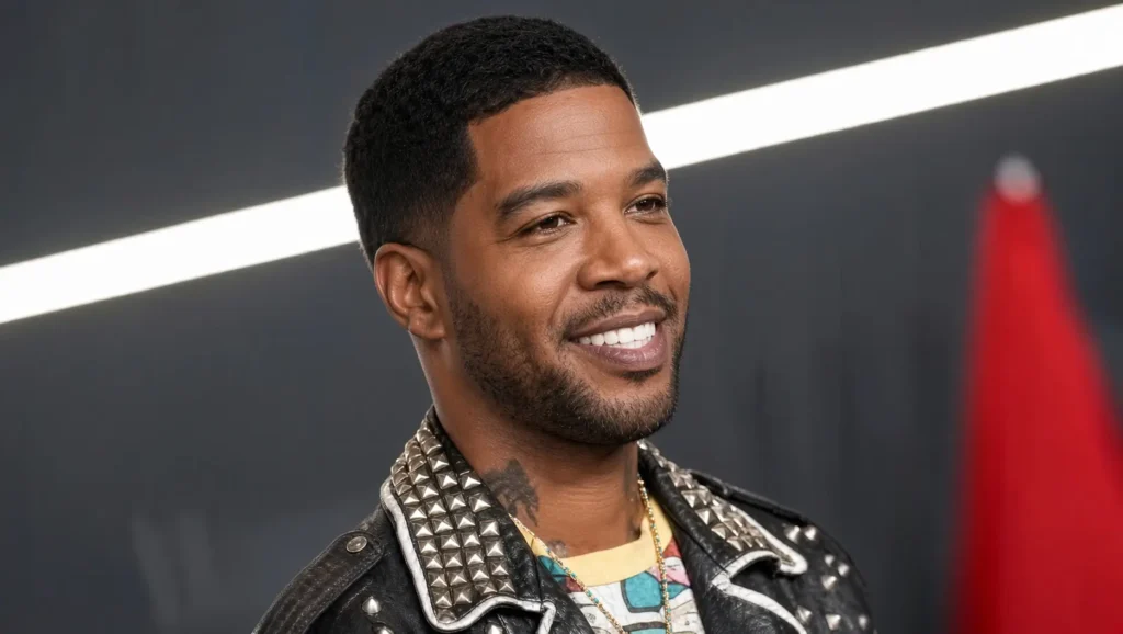 Kid Cudi smile in a stud black leather jacket with pattern lapels against a dark backdrop and red object