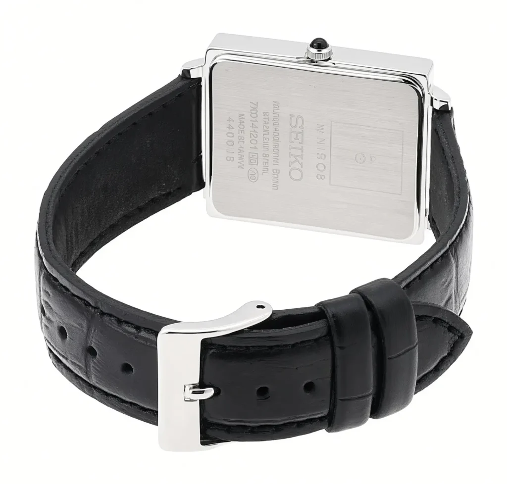 Reverse of a rectangular Seiko watch showing a brushed steel caseback, crown, engraved text and black leather strap on white