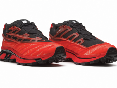 Pair of red and black Salomon trail shoes with rugged black lugs and angular red overlays on a white background