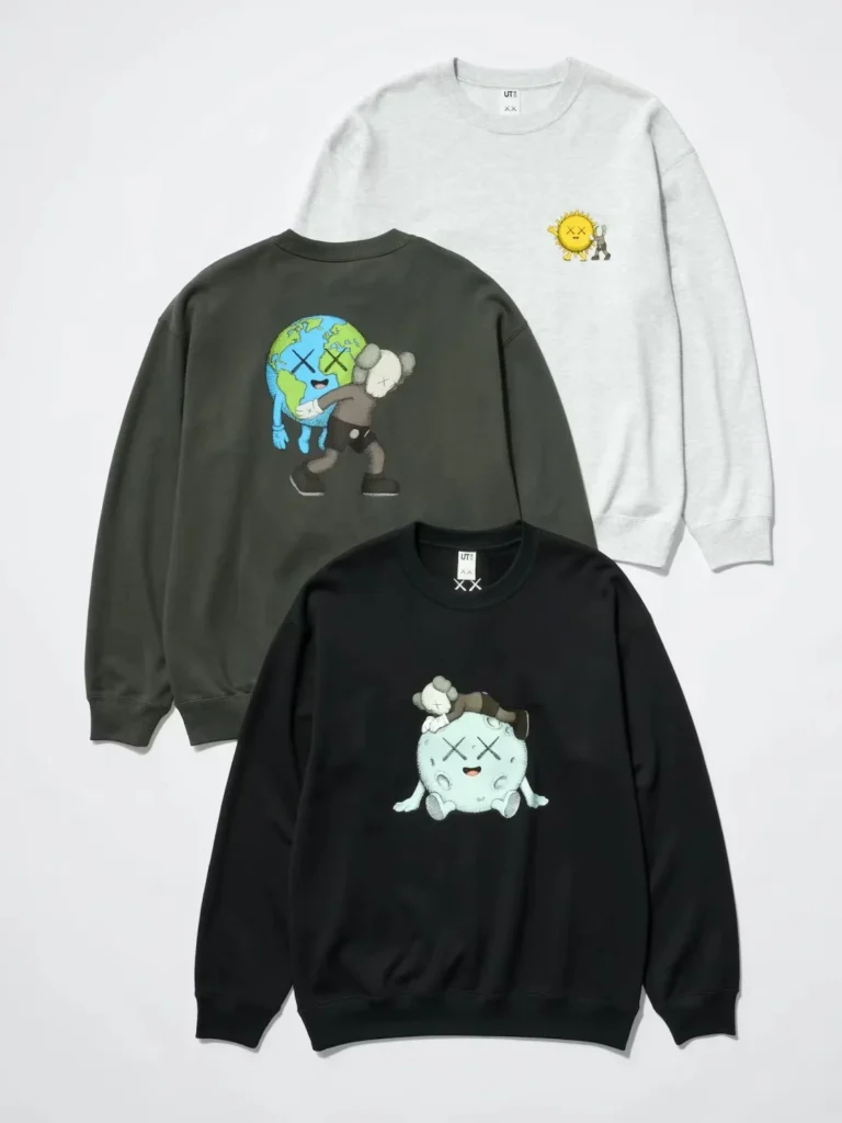 Three KAWS graphic sweatshirts in light gray, dark gray and black, arranged on a white background