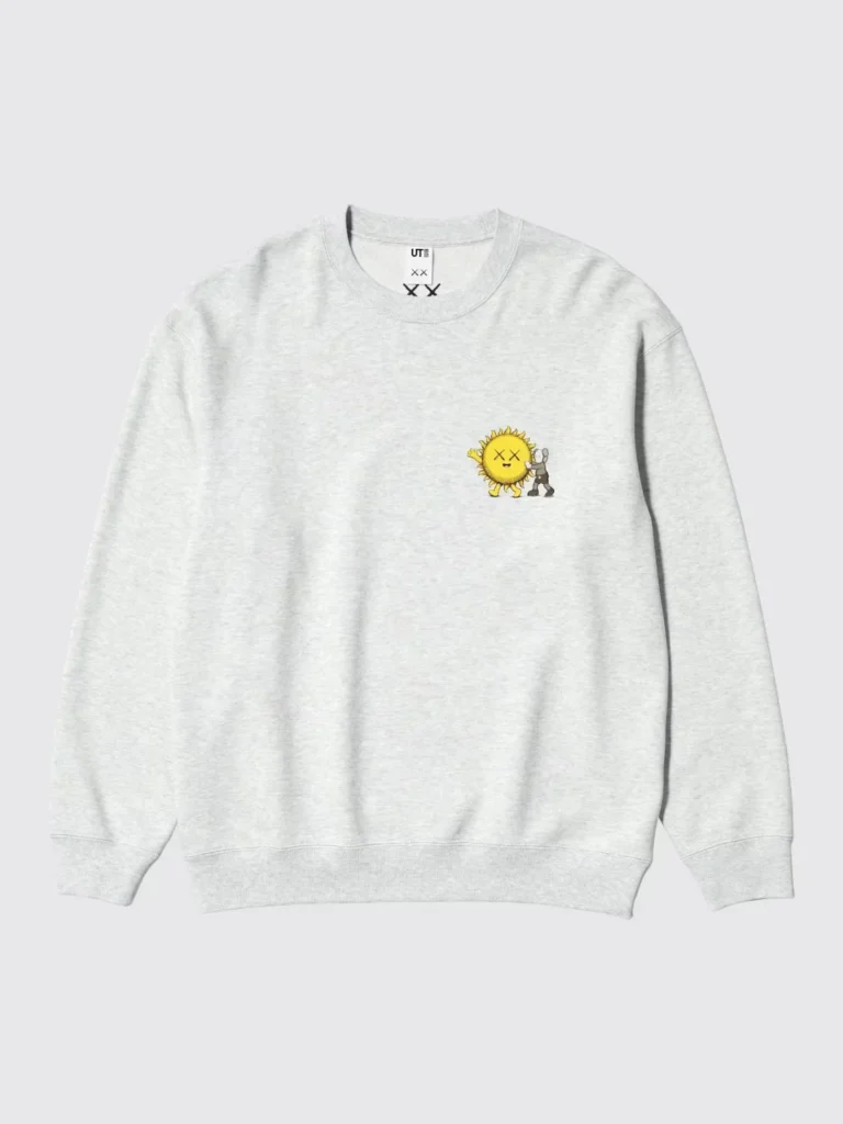 Light gray sweatshirt with ribbed cuffs and hem, featuring a small yellow sun and gray character graphic on the chest