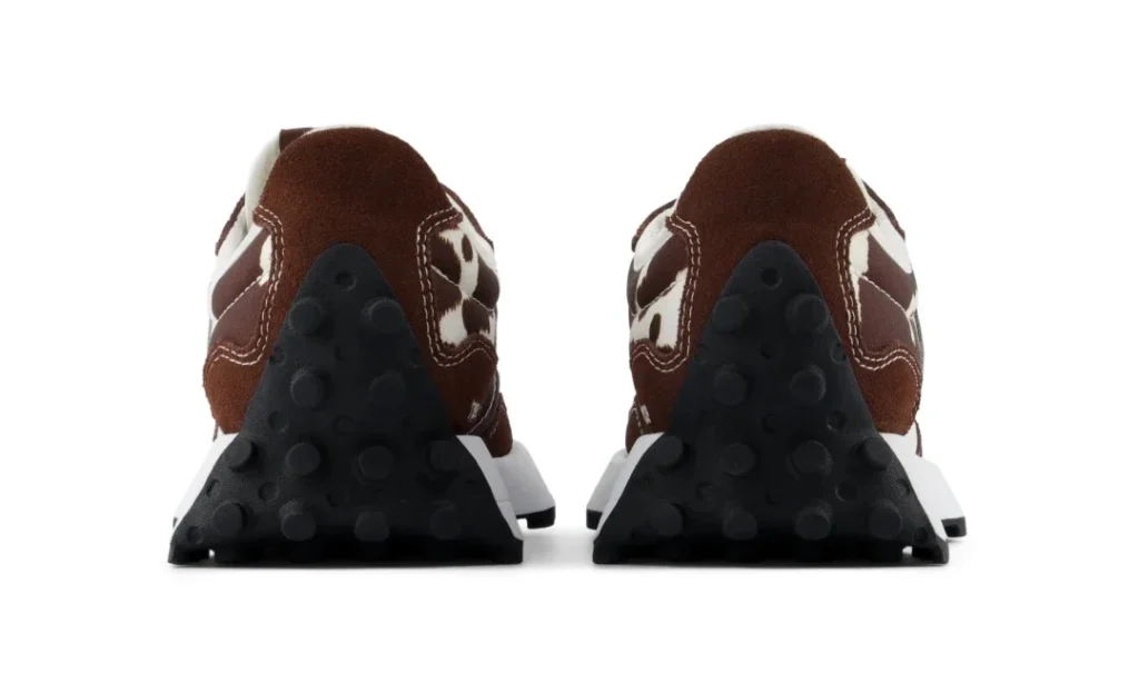 Rear view of brown and white shoe with black studded rubber outsoles, positioned side by side on a white background