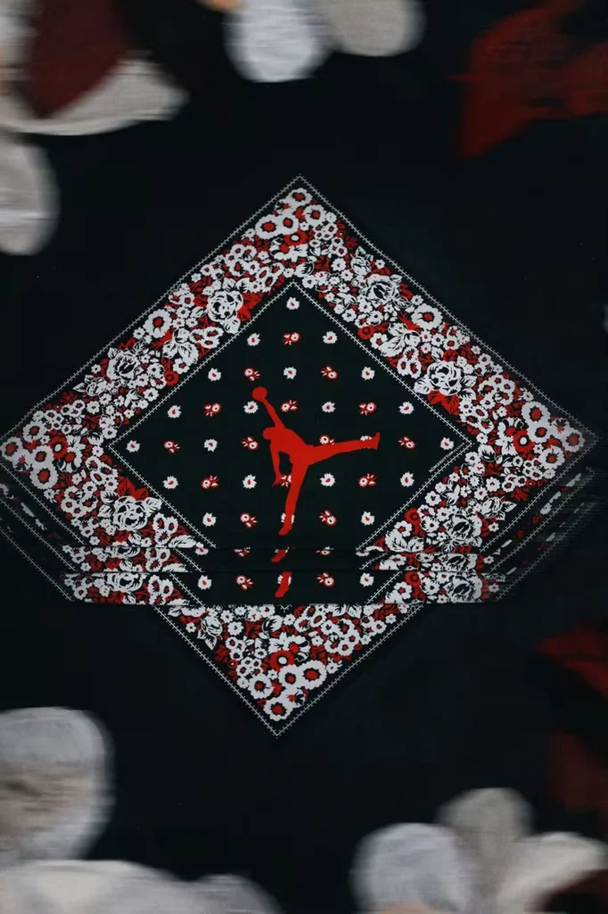 Black garment featuring a red, white and black floral diamond patch with a red jumping basketball-player silhouette