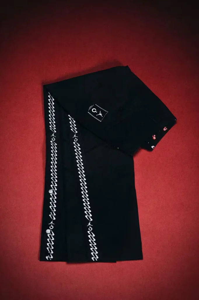 Black Jordan shorts with white vertical graphics and small red-and-white details, laid flat on a red textured surface