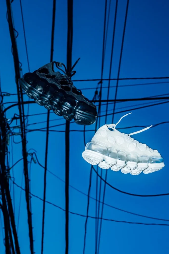 Black and white futuristic sneakers float against a vivid blue background crisscrossed by black wires