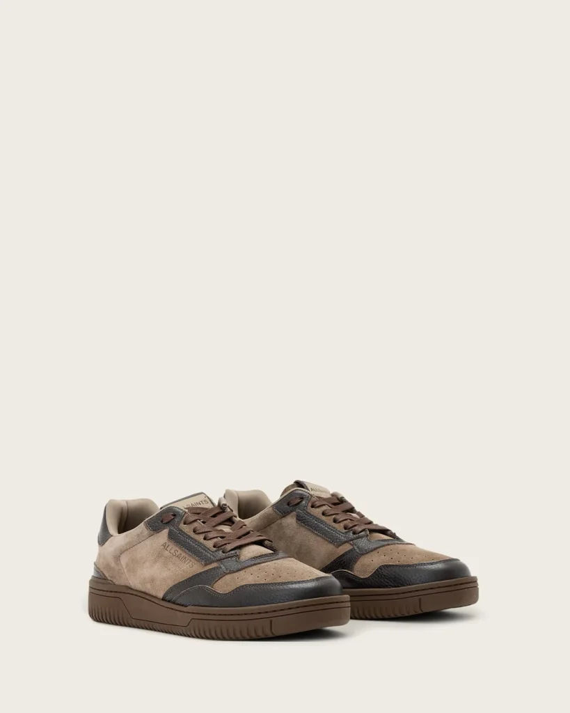 Pair of tan and dark brown leather low-top sneakers with textured panels and thick brown soles on a plain background