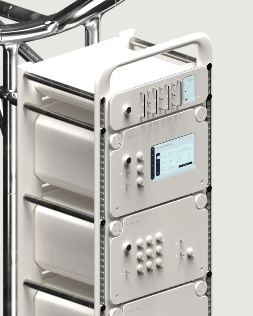 White modular equipment rack with shelves, control panels, knobs, switches and small blue-green display, framed by chrome