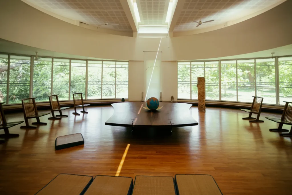 Circular sunlit room with curved windows, wooden floor, rocking chairs, and a globe on a central table