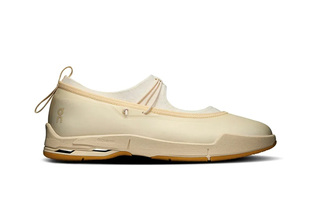 Cream slip-on shoe with elastic collar, side toggle, textured sole, gum outsole, and visible On logo against white