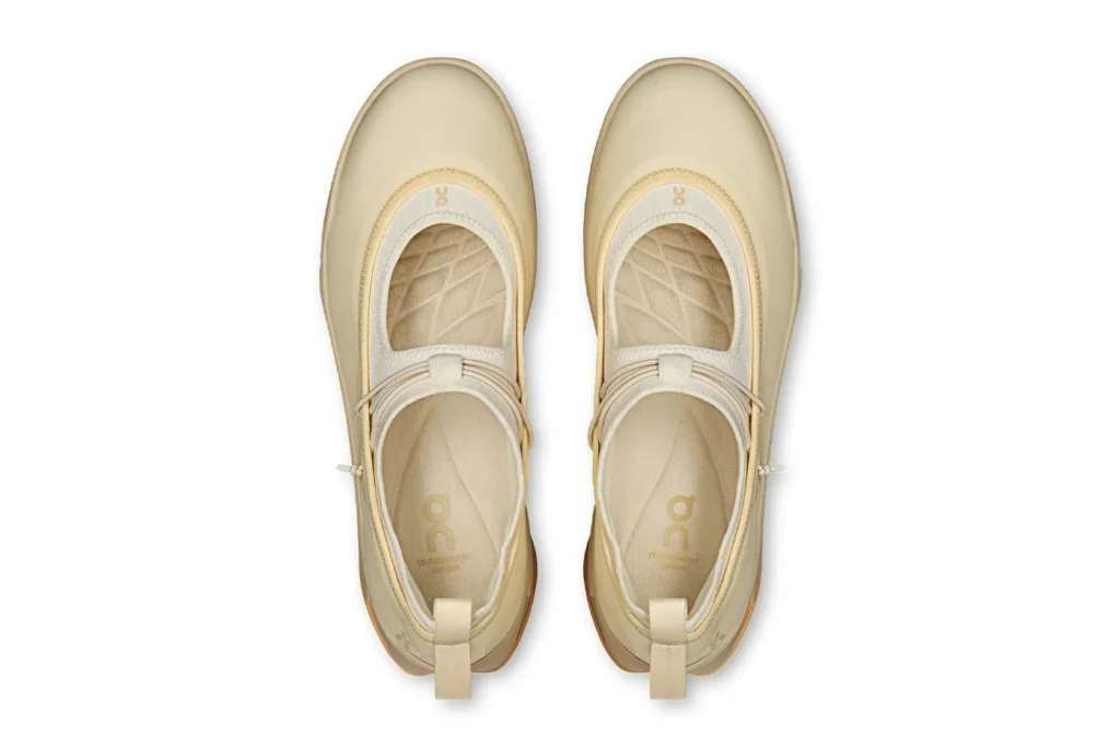 Top-down view of a matching pair of cream slip-on sneakers with layered straps and textured insoles on white background