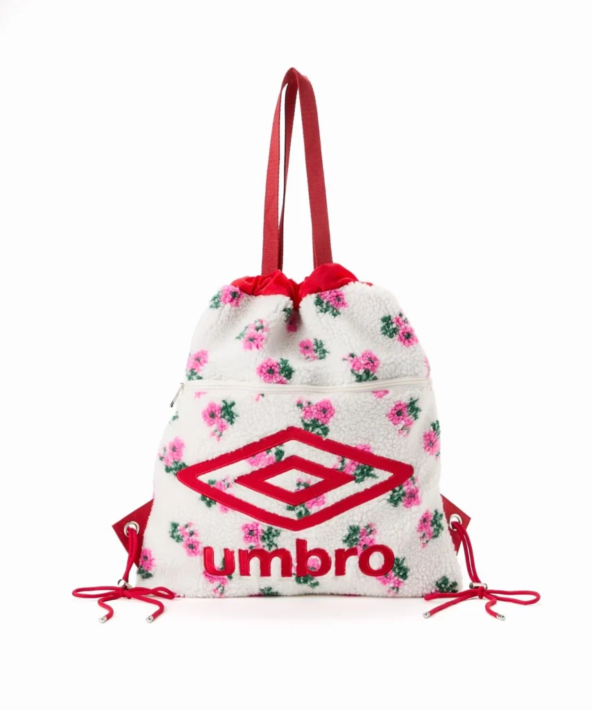 White sherpa Umbro drawstring backpack with pink floral print, red straps, logo and zipper, on white background