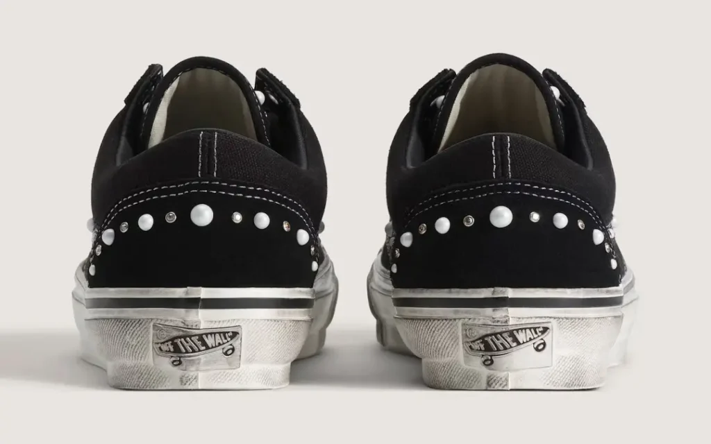 Rear view of black Vans sneakers with white soles and pearl and stud embellishments across the heels
