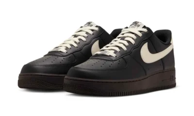 Pair of black Nike Air Force 1 sneakers with cream swooshes and laces on a white background