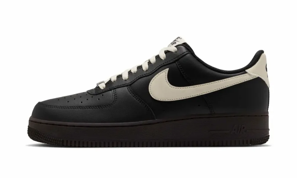 Black low-top sneaker with a white swoosh and laces, shown in side profile against a white background