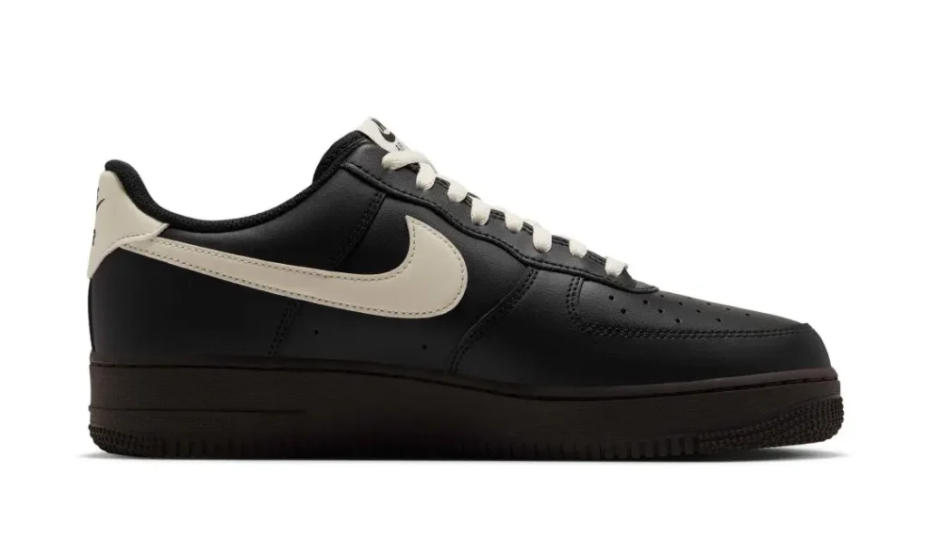 Black low-top sneaker with cream swoosh and laces, shown in side profile against a white background