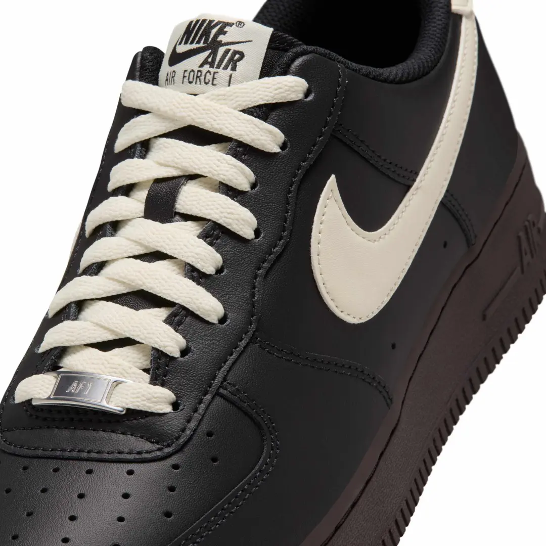 Close-up of a black Nike Air Force 1 sneaker with white laces and a cream swoosh