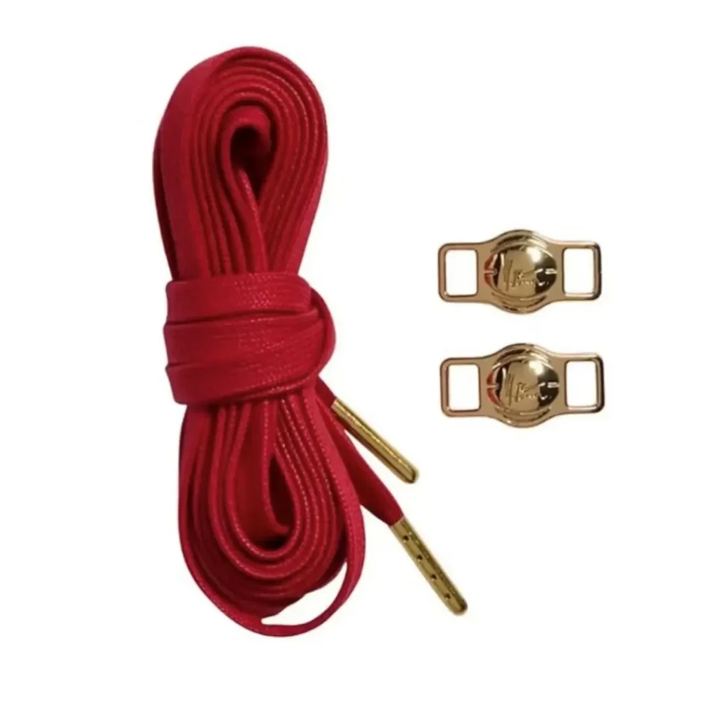 Coiled red leather shoelaces with gold-toned metal aglets and two matching rectangular fasteners on a white background