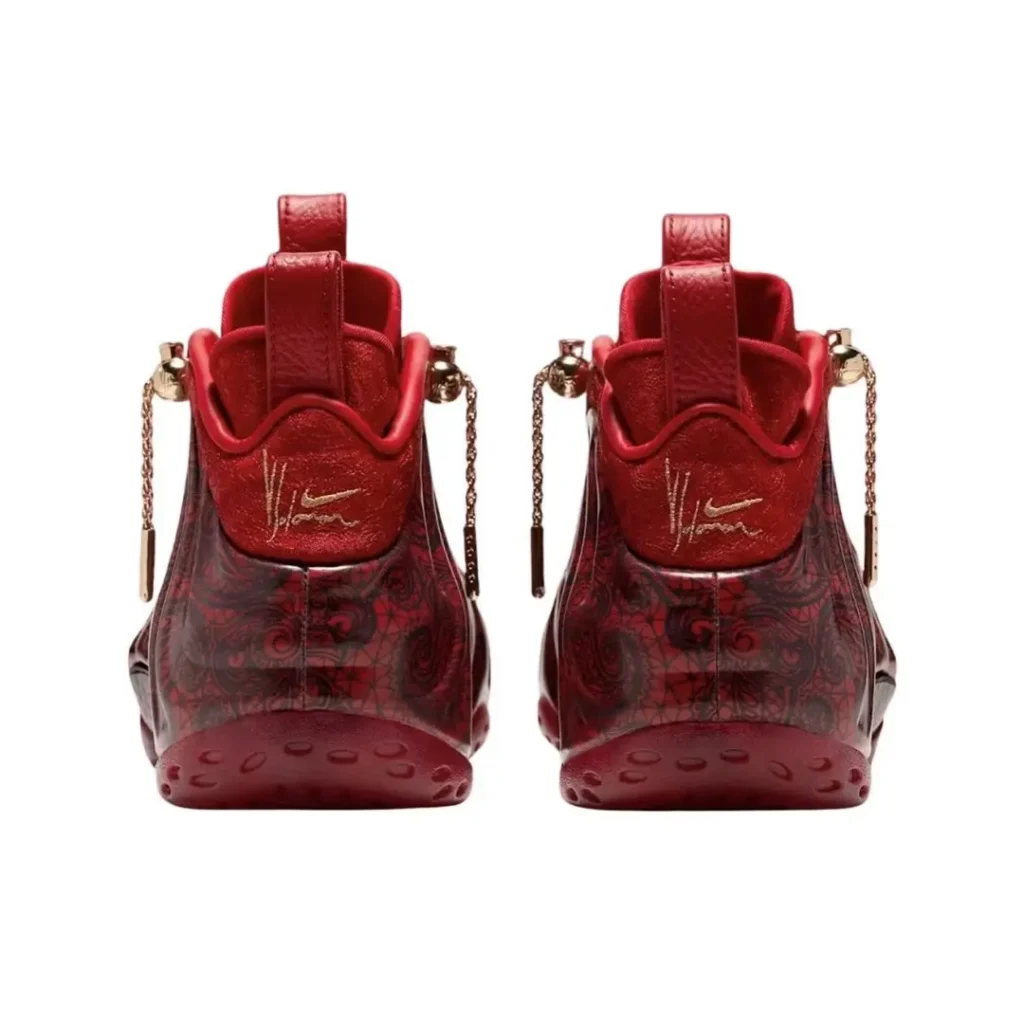 Pair of red high-top sneakers with patterned translucent panels, gold script, and dangling chain details on a white