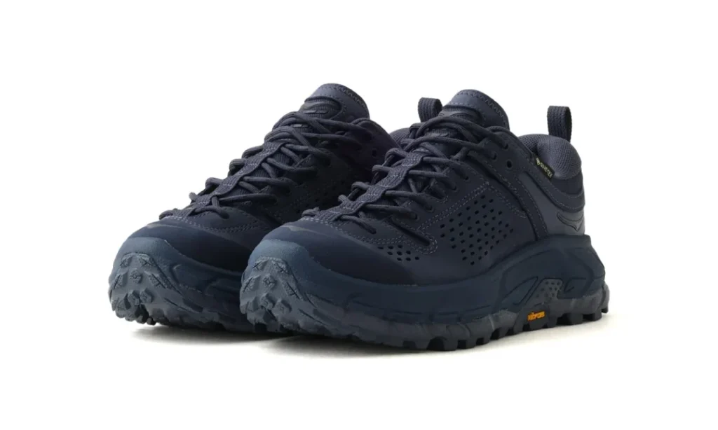 Pair of black low-top hiking shoes with rugged lugged soles and perforated side panels on a white background