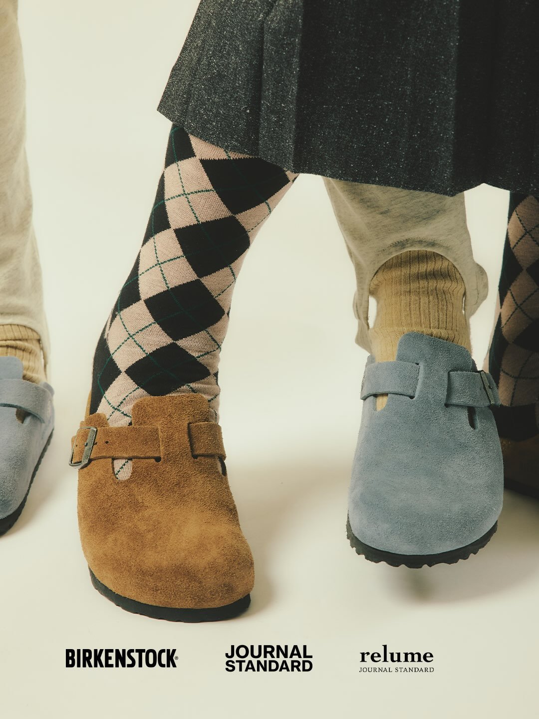 Close-up of three people wearing Birkenstock clogs, including brown, blue, and gray pairs with patterned socks