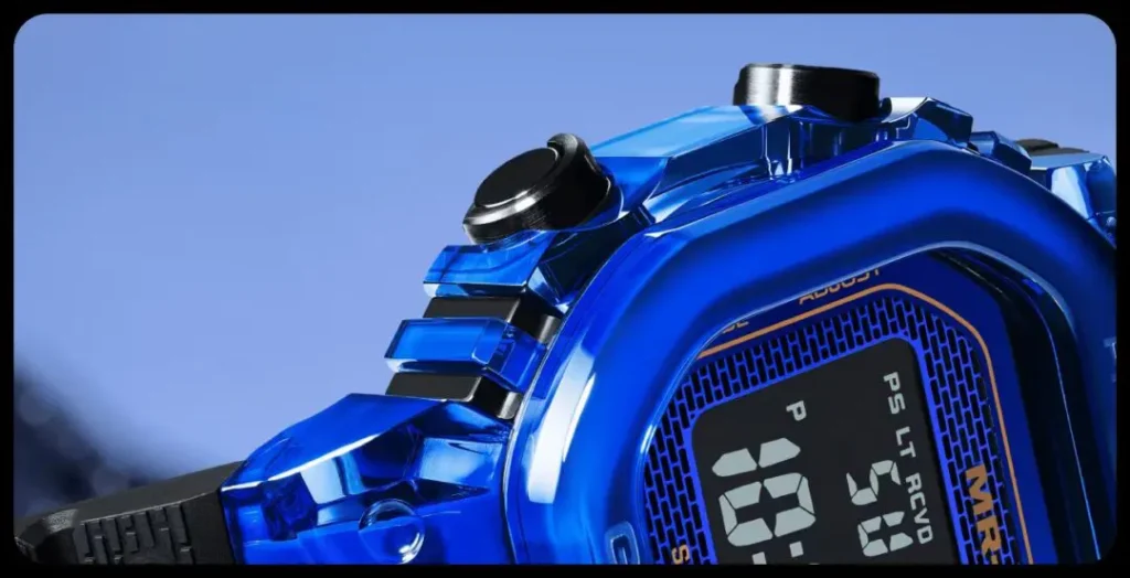 Close-up of a blue digital sports watch showing part of its display, black buttons and textured strap against a blue