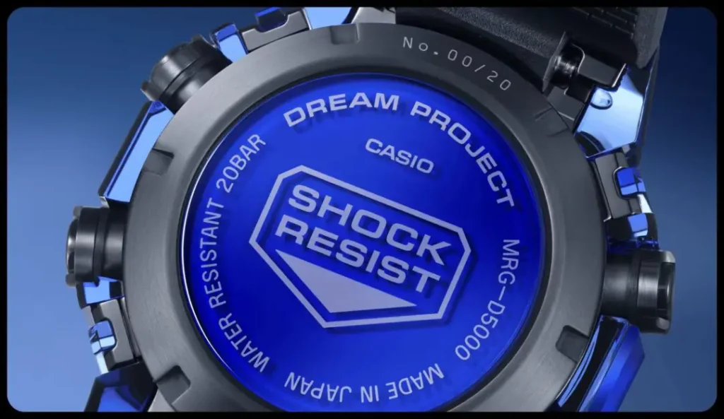 Close-up of a blue and black Casio G-Shock watch face displaying “SHOCK RESIST” and “DREAM PROJECT” lettering