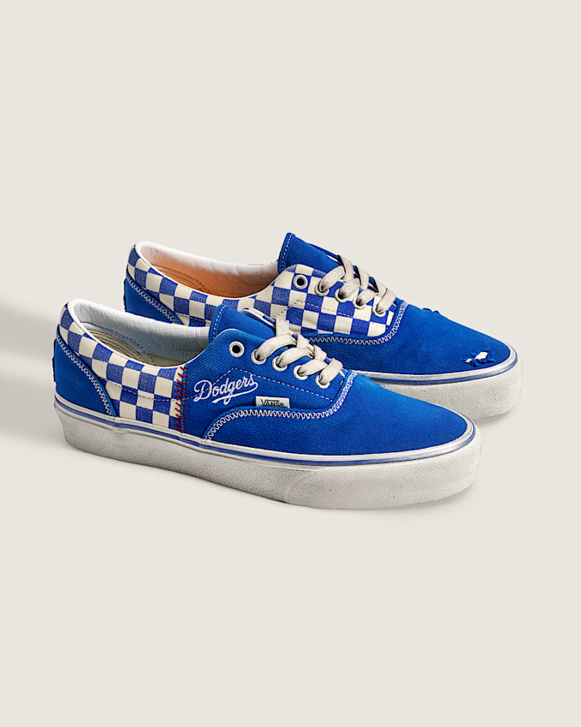 Two blue Vans sneakers with white checkered panels and Dodgers branding on a light background