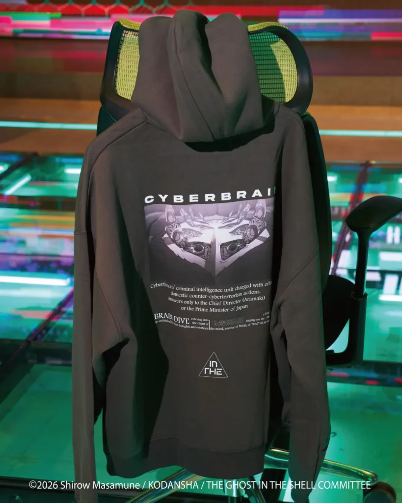 Black hooded sweatshirt displayed on a gaming chair, featuring Cyberbrain text, anime artwork, and white lettering against
