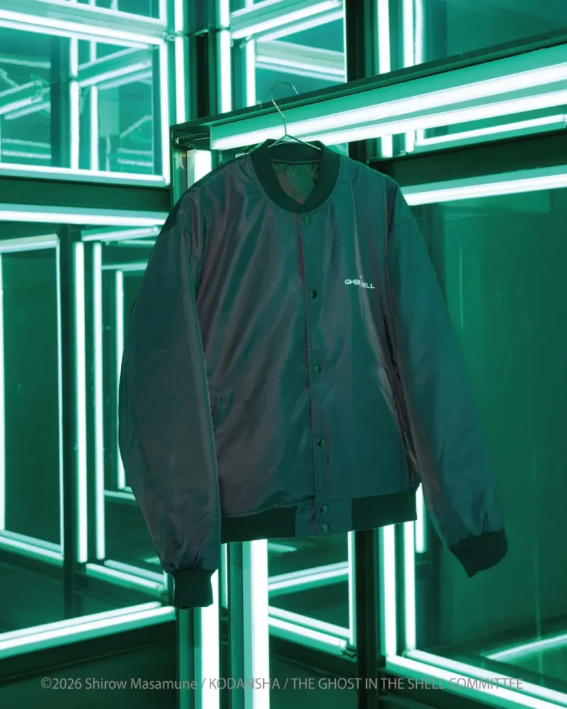 Dark satin bomber jacket with ribbed collar and cuffs hangs on a wire hanger amid glowing green fluorescent light frames