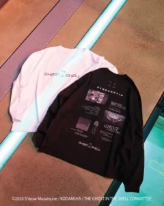 Black and white Ghost in the Shell graphic long-sleeve shirts arranged on a textured floor beside glowing tubes