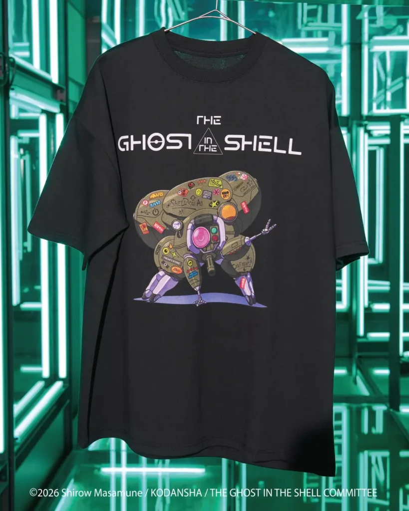 Black T-shirt on a hanger with “The Ghost in the Shell” text and a colorful robotic character graphic, against neon green