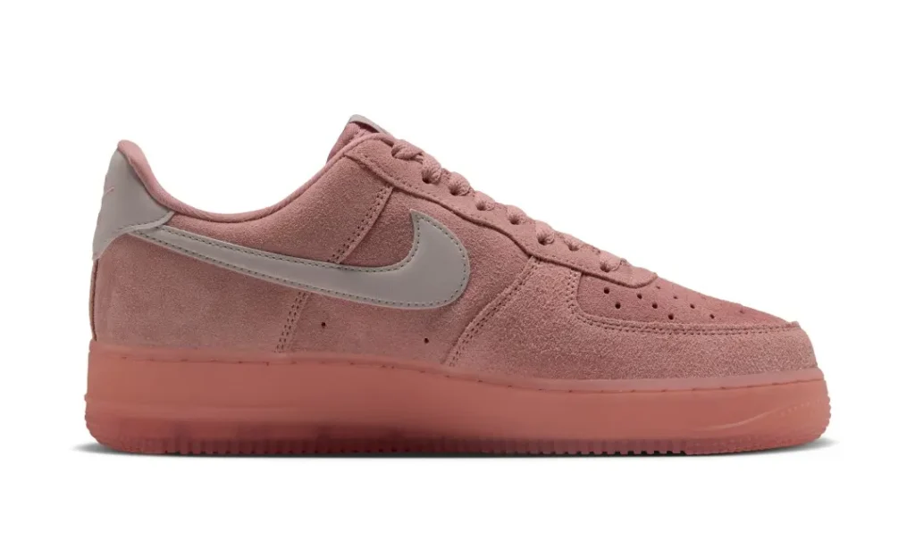 Pink suede Nike low-top sneaker with a pale swoosh and matching thick rubber sole on a white background
