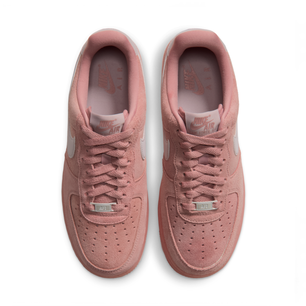 Pair of pink Nike Air Force 1 shoe with white swooshes, viewed from above on a white background