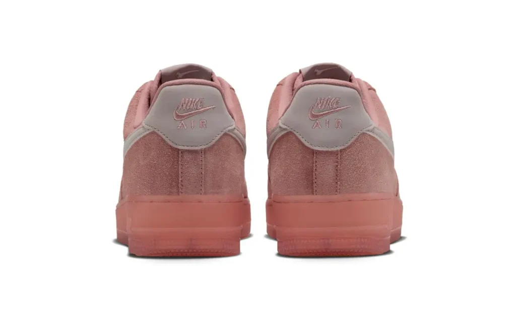 Rear view of a pair of dusty pink Nike Air sneakers with suede uppers and translucent rubber soles on a white background
